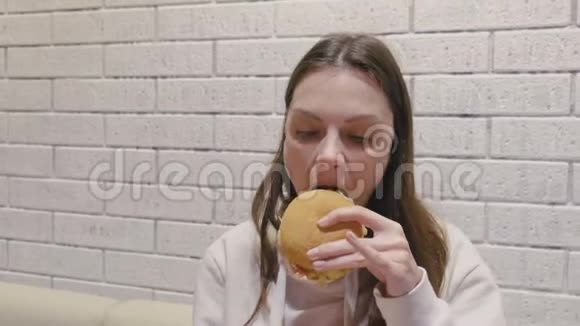 女人在咖啡馆里津津有味地吃着汉堡包视频的预览图
