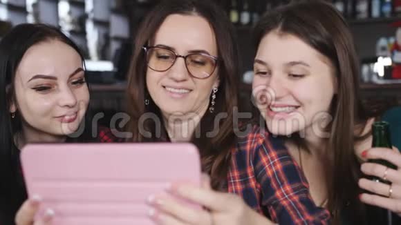 有趣的女孩在餐厅的桌子上聊天在平板电脑上观看照片视频的预览图