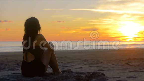 性感的女人在沙滩上放松地看美丽的日落视频的预览图
