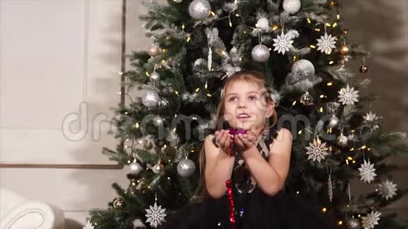 小女孩手里拿着闪闪发光的纸屑对着圣诞树视频的预览图