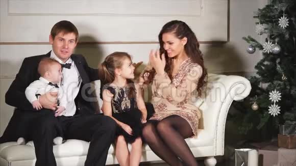 圣诞节晚上男人女人和他们的小孩在白色沙发上休息视频的预览图