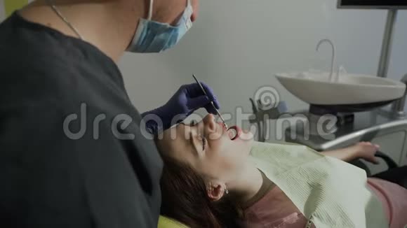 病人的牙齿健康女孩牙医通过镜子检查病人牙齿视频的预览图