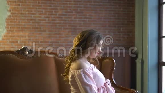 美丽的孕妇穿着优雅的粉红色连衣裙坐在家里的沙发上视频的预览图