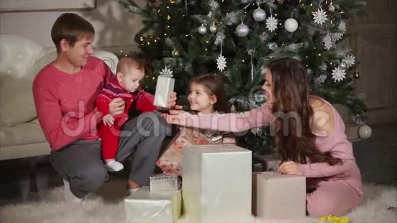 年轻女子正在给她的丈夫女儿和小儿子送圣诞礼物视频的预览图
