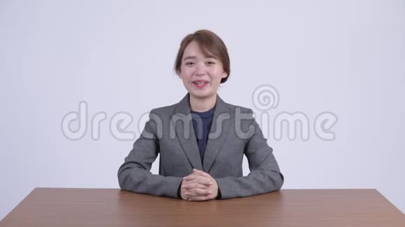 年轻快乐的亚洲女商人坐在办公桌前聊天视频的预览图