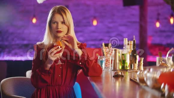 一位漂亮的年轻女子坐在酒保摊边喝着吸管里的饮料视频的预览图