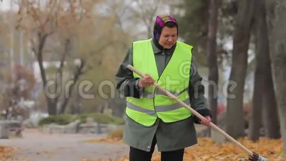 不快乐的超重女人在秋天扫荡城市公园勤劳的人视频的预览图