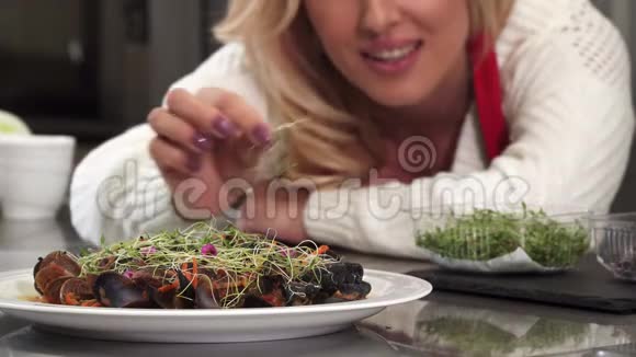 漂亮的女人把贻贝盘在盘子上装饰在家里准备食物视频的预览图