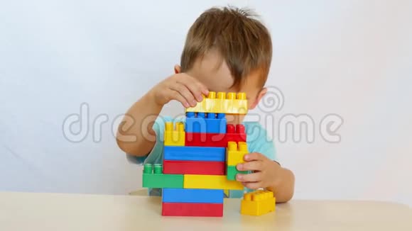 一个小男孩正在桌子上建一座彩色积木塔视频的预览图