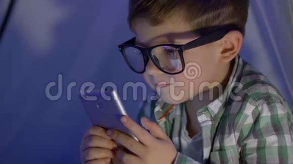 戴眼镜的上网儿童在wigwam特写镜头中观看视频进入手机视频的预览图