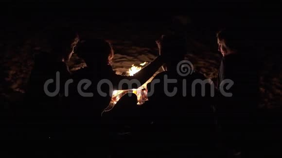 傍晚时分年轻人坐在炉火旁拥抱在一起快乐的朋友视频的预览图