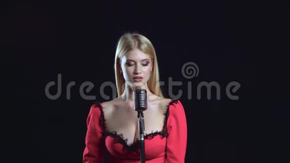 女孩用复古麦克风用柔和的声音唱歌黑色背景视频的预览图
