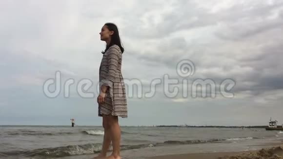 年轻漂亮的女孩正沿着沙滩散步视频的预览图