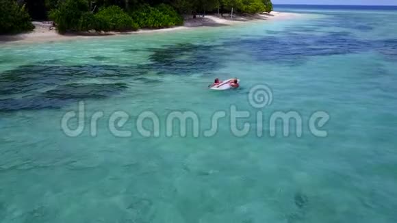 两个漂亮的年轻女孩坐在冲浪板上在温暖的蓝色海水中鸟瞰视频的预览图
