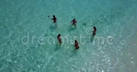 5名年轻女子在阳光岛白沙滩碧海天的海水上从空中无人机观看打球视频的预览图