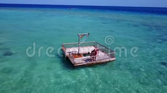 两个年轻人在浮筒上进行浪漫的日光浴在美丽清澈的水蓝色海水中鸟瞰视频的预览图