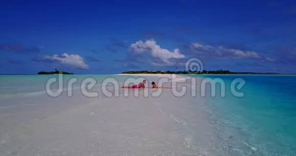 2个年轻人浪漫的情侣日光浴无人驾驶飞机在沙滩上看着白色沙滩和美丽的风景视频的预览图