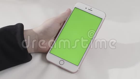 手持触摸绿色屏幕智能手机在白色背景库存录像手拿带chroma键的手机视频的预览图