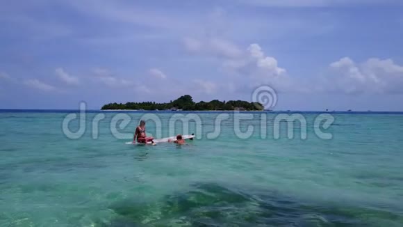 V08412两个漂亮的年轻女孩坐在冲浪板上在温暖的蓝色海水中鸟瞰天空视频的预览图