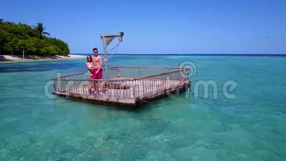 V08577两位年轻人在美丽的碧蓝色海水中在浮舟上享受浪漫的日光浴视频的预览图