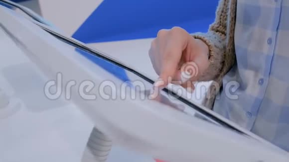 女性手使用触摸屏显示地板站立白色平板电脑亭视频的预览图