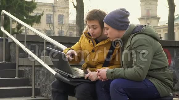 两个学生用笔记本电脑坐在公园的长椅上视频的预览图