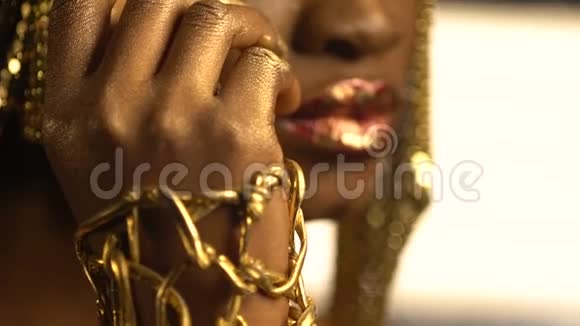 美丽迷人的非洲女人的肖像有红色光泽的嘴唇和金色的壶青铜眼影和眼线视频的预览图