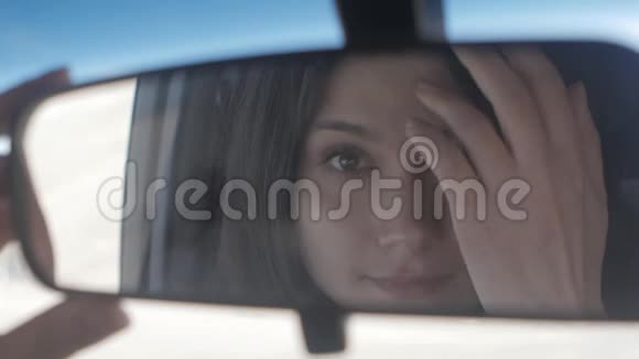 年轻漂亮的女人坐在车里看后视镜视频的预览图