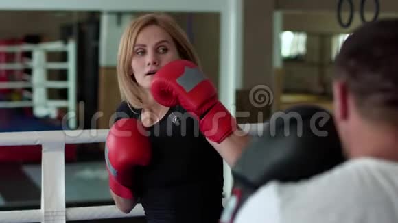 女子拳击训练与拳击场教练一起踢腿视频的预览图