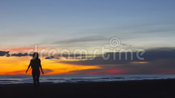 美丽的年轻女子在日落时快乐地在海边跑来跑去视频的预览图