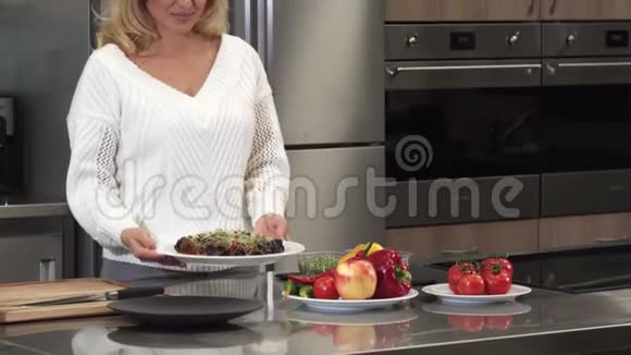 做饭后美丽的成熟女人对着镜头微笑摆着一道菜视频的预览图