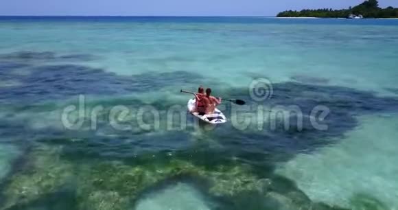 V08244两个漂亮的年轻女孩坐在冲浪板上在温暖的蓝色海水中鸟瞰天空视频的预览图