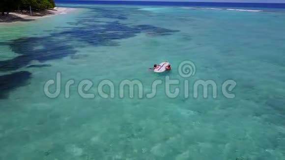 V08378两个漂亮的年轻女孩坐在冲浪板上在温暖的蓝色海水中鸟瞰天空视频的预览图