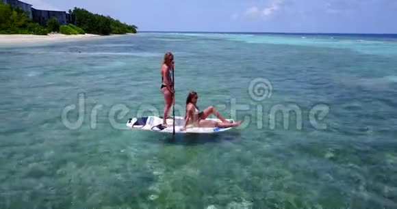 V083282美丽的年轻女孩在冲浪板上可以在温暖的蓝色海水中鸟瞰视频的预览图
