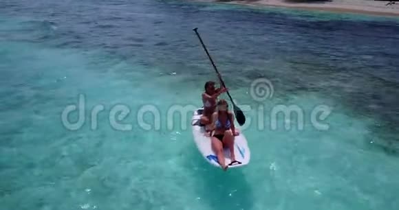 V082702美丽的年轻女孩在冲浪板上可以在温暖的蓝色海水中鸟瞰视频的预览图