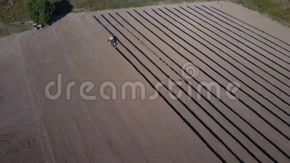 棕地上的农用拖拉机无人机绕着一辆拖拉机在农村的田野上工作视频的预览图