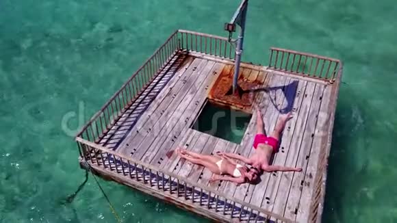 V085642名青年夫妇在浮舟上进行浪漫的日光浴在美丽清澈的海水中进行鸟瞰视频的预览图