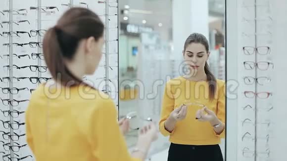 保健视力和视力的概念快乐的女人在镜子前的光学商店选择眼镜视频的预览图