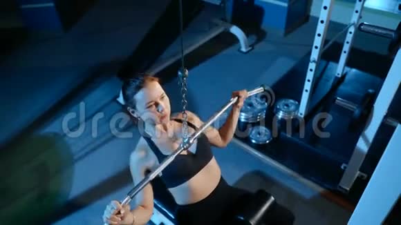 这个女孩从事健身房模拟器上的牵引上部单元4k视频的预览图