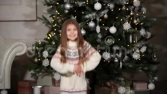 可爱的小女孩在圣诞树附近快乐地跳跃视频的预览图