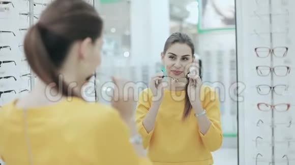 保健视力和视力的概念快乐的女人在镜子前的光学商店选择眼镜视频的预览图
