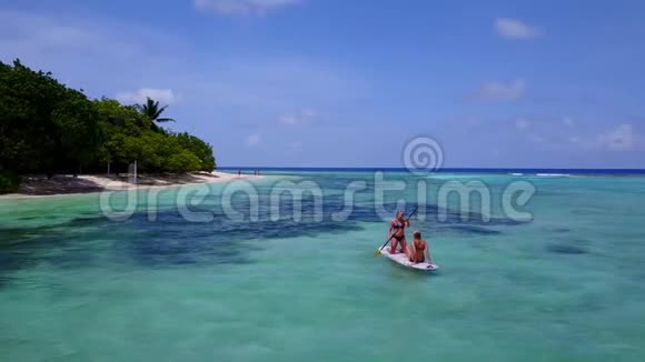 V08408两个年轻漂亮的女孩坐在冲浪板上在温暖的蓝色海水中俯瞰空中景色视频的预览图