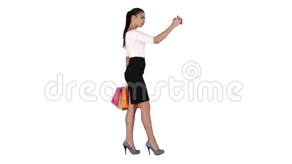 漂亮的年轻女人有着长长的黑发拿着不同的空白购物袋在白色背景上自拍视频的预览图