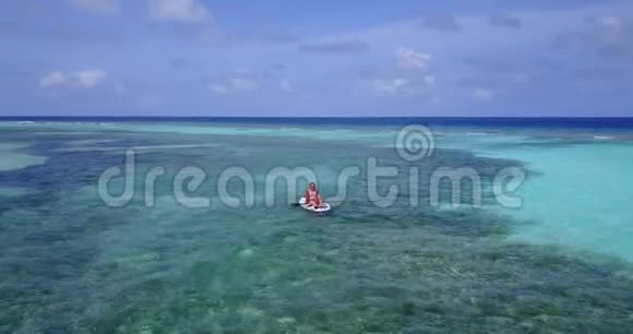 V083002个漂亮的年轻女孩坐在冲浪板上在温暖的蓝色海水中鸟瞰视频的预览图