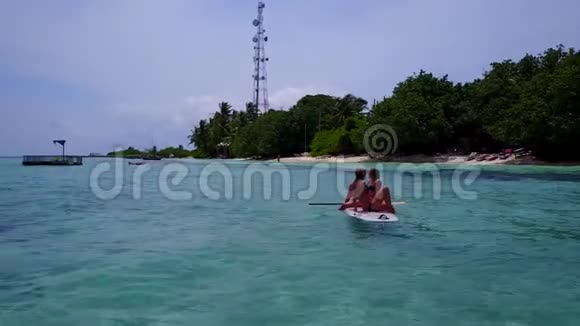 V08394两个漂亮的年轻女孩坐在冲浪板上在温暖的蓝色海水中鸟瞰视频的预览图