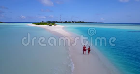 两个浪漫的年轻人在热带地区的无人机空中飞行视野中牵手散步视频的预览图