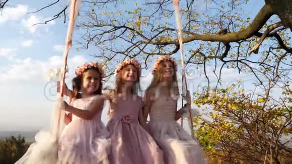 三个漂亮的小女孩在一棵大树下荡秋千视频的预览图