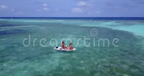 V08290两个漂亮的年轻女孩坐在冲浪板桨板上在温暖的蓝色海水中鸟瞰视频的预览图