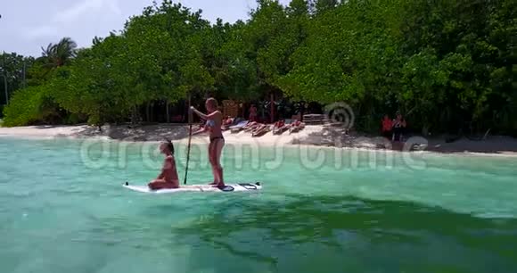 V08232两个漂亮的年轻女孩坐在冲浪板上在温暖的蓝色海水中鸟瞰视频的预览图