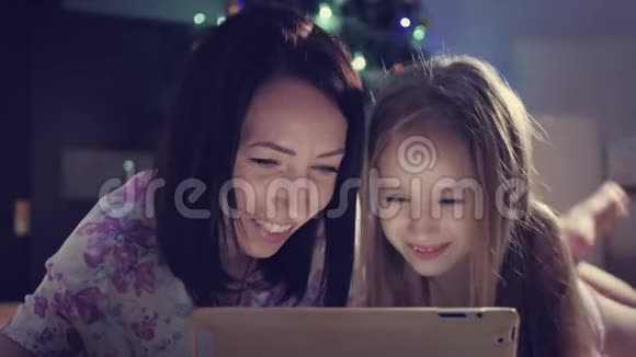 一家人的母亲和女儿在躺在地上数字平板电脑上的礼物圣诞节视频的预览图